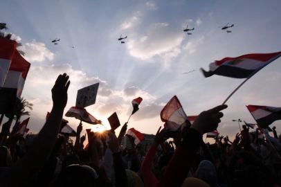 Egyptian army helicopters hoisting the national flag fly over demonstrators on Tahrr Square.